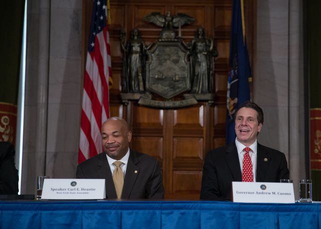 Carl Heastie and Andrew Cuomo, in suits in the wood paneled executive building, are smiling
